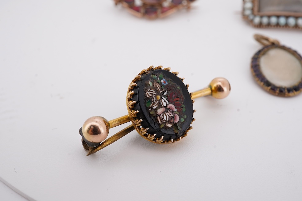 Three assorted Victorian brooches including a 9ct and garnet cluster by Murrle Bennett & Co, 27mm, a micro mosaic bar brooch and a yellow metal and split pearl mourning brooch, together with a gem set oval pendant. Condi
